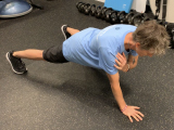 trainer doing plank with shoulder touches