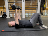 personal trainer doing dumbbell chest press